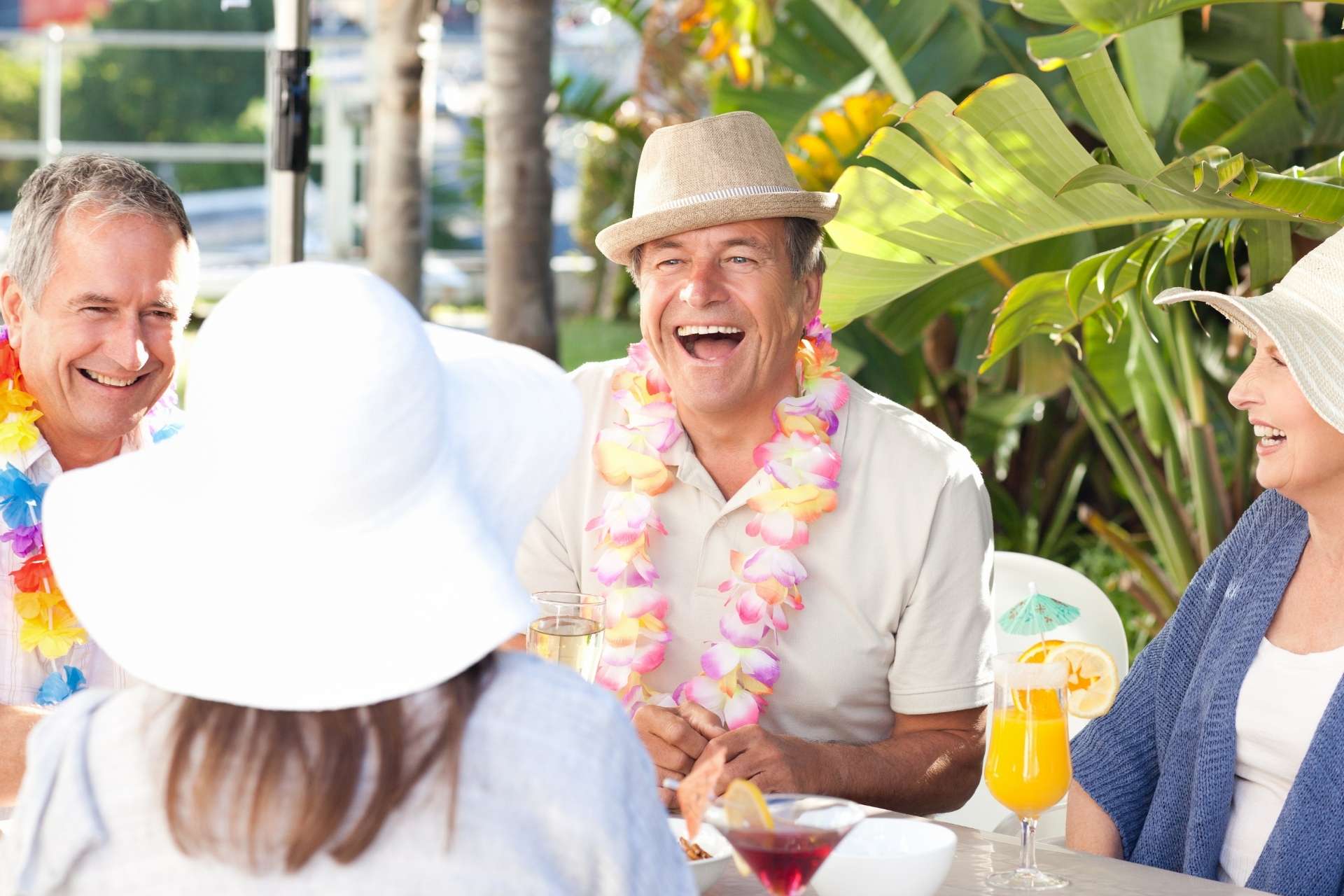 A group of seniors enjoying a tropical environment with drinks and leis.